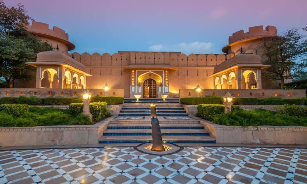 The fort-style entrance courtyard of The Oberoi Rajvilas, Jaipur, at dusk