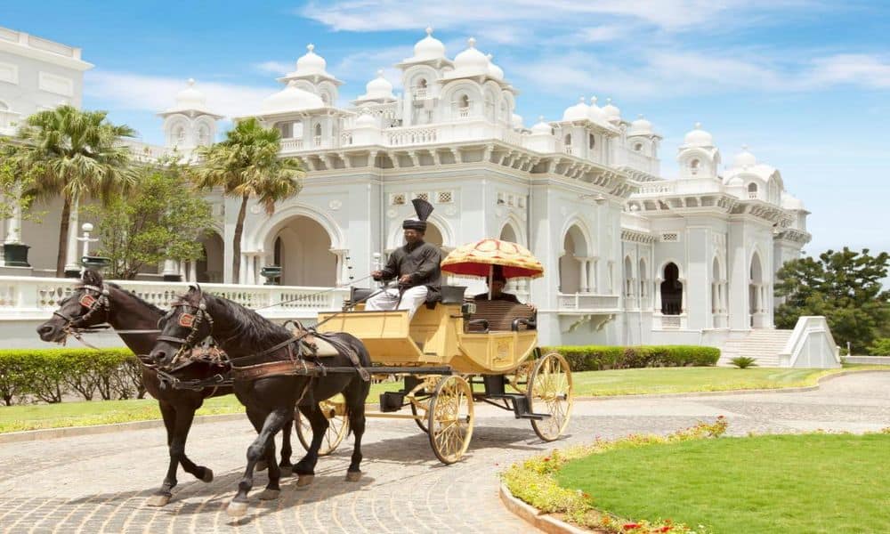 A horse-drawn carriage in front of the white facade of Taj Falaknuma Palace