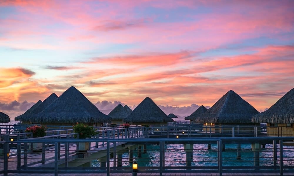 Thatched overwater bungalows at sunset