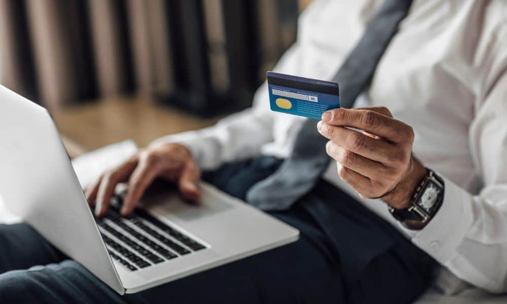 Person holding a payment card while booking on a laptop