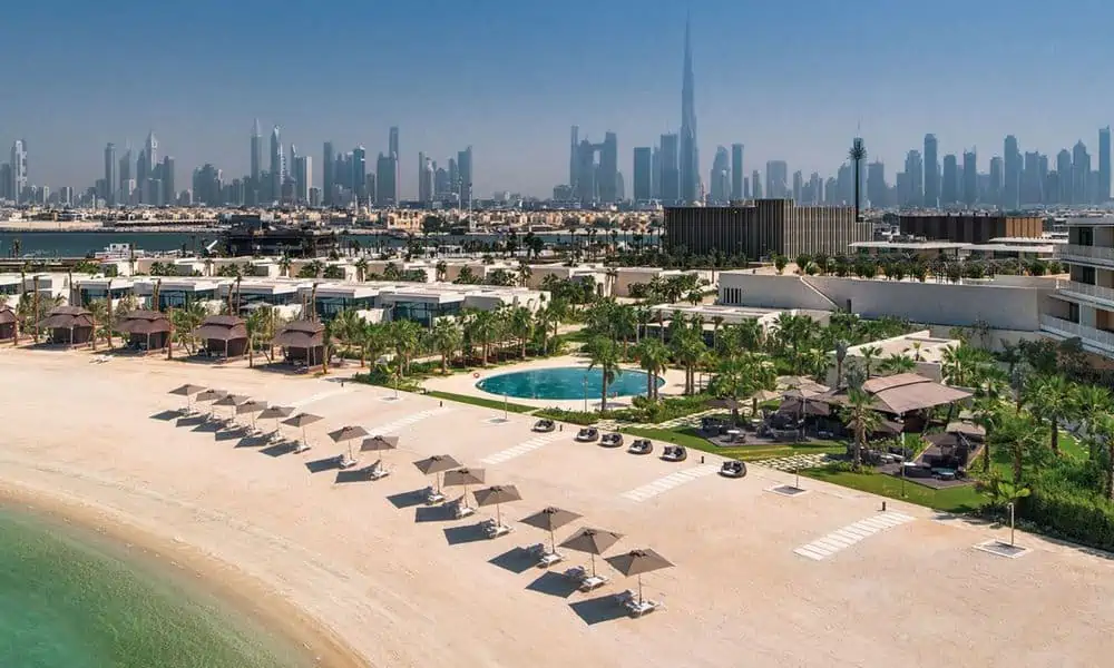 Aerial view of Bvlgari Resort Dubai's beach and villas on Jumeira Bay with the Dubai skyline behind