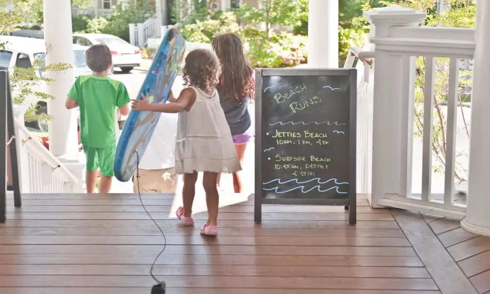 Children carrying a boogie board past a beach notice board at The Nantucket Hotel