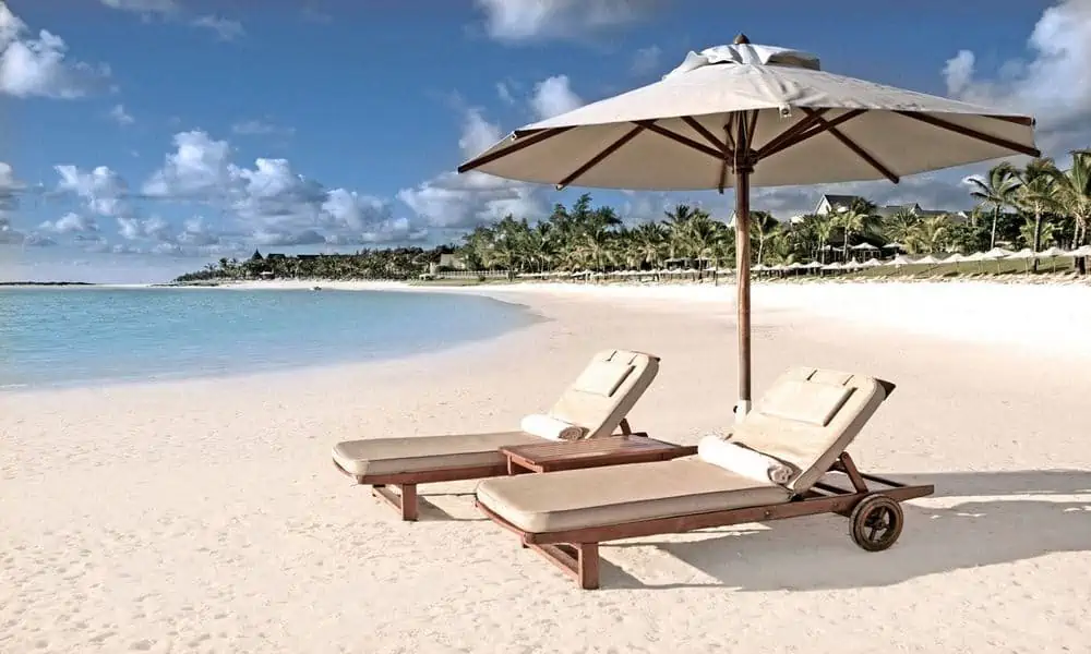 Sun loungers under a parasol on the beach at The Residence Mauritius