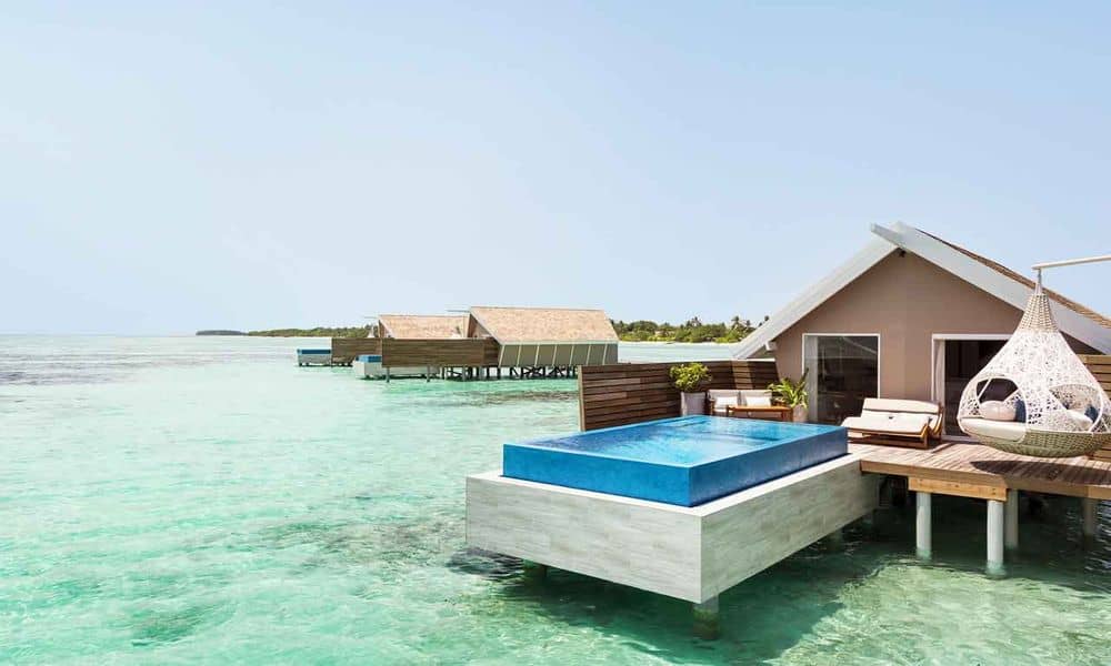 Overwater villa with a raised private pool and hanging chair at LUX* South Ari Atoll