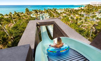 Rider in a tube at the top of a water slide at Aquaventure, Atlantis Paradise Island, with the Bahamas coast behind