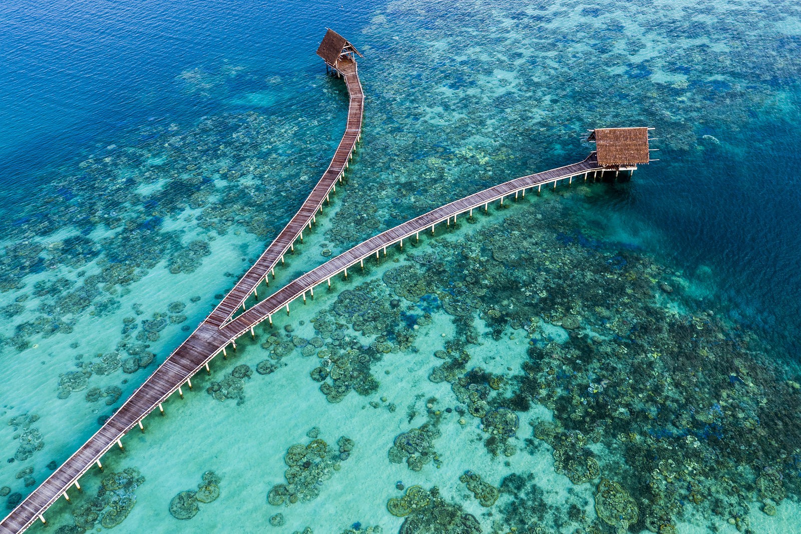 Aerial view of jetties and thatched pavilions over the reef at Bawah Reserve