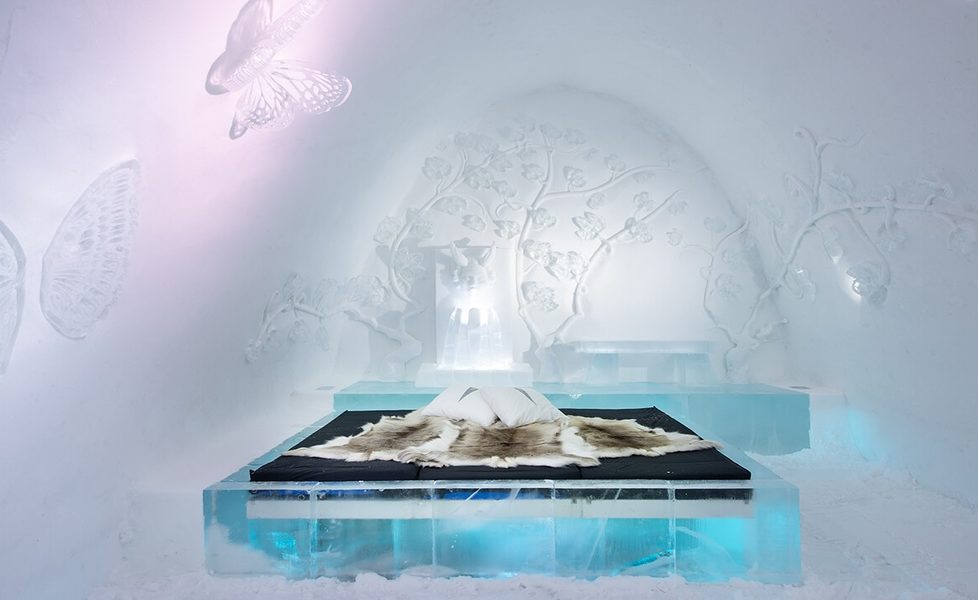 Art suite at ICEHOTEL, Jukkasjärvi, with an ice bed under reindeer hides and butterflies carved in the snow wall (a past season's design)