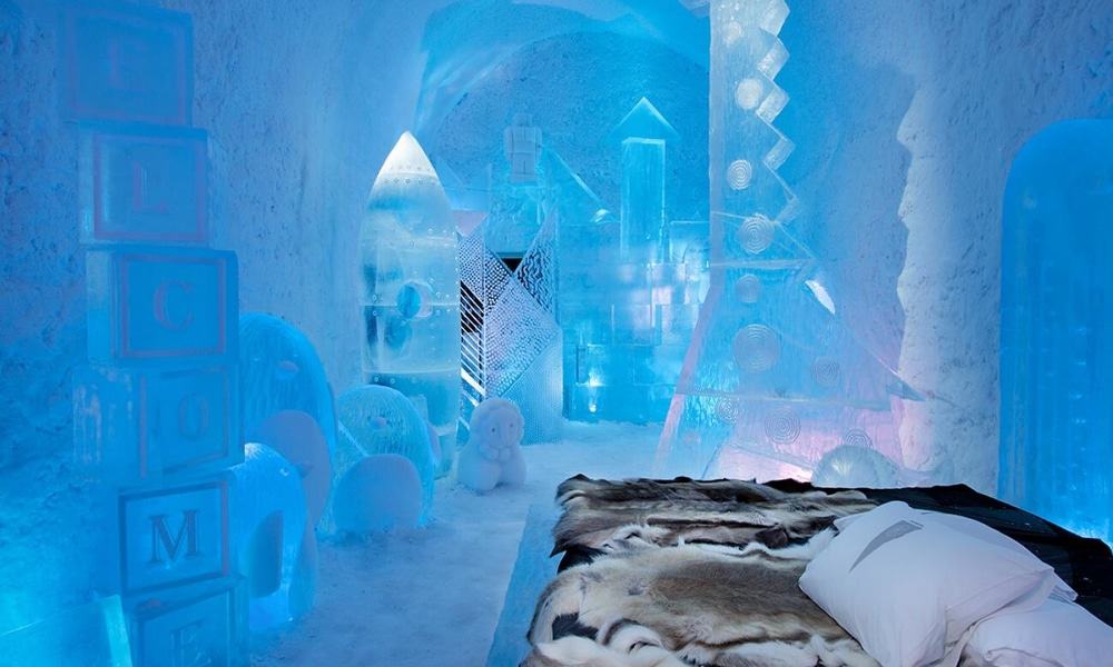 Art suite at ICEHOTEL with ice sculptures of children's building blocks and a rocket around a fur-covered bed (a past season's design)