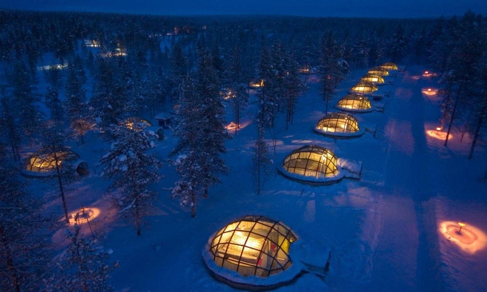 Glass igloos at Kakslauttanen Arctic Resort lit at night among snow-covered pines