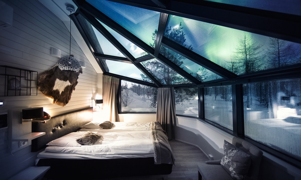Inside a glass igloo at Santa's Igloos Arctic Circle: twin beds under a glass roof with the northern lights above