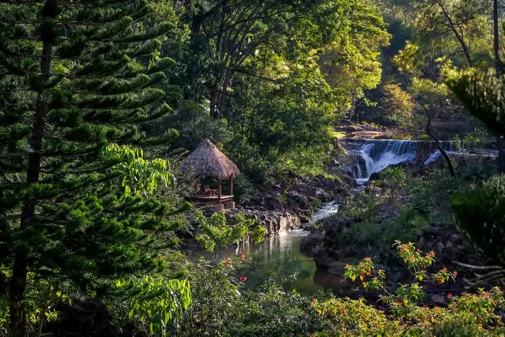 A thatched cabana by a waterfall in the pine forest at Blancaneaux Lodge