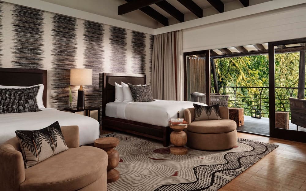 A bedroom at the Nyungwe resort with two beds and a balcony facing the forest